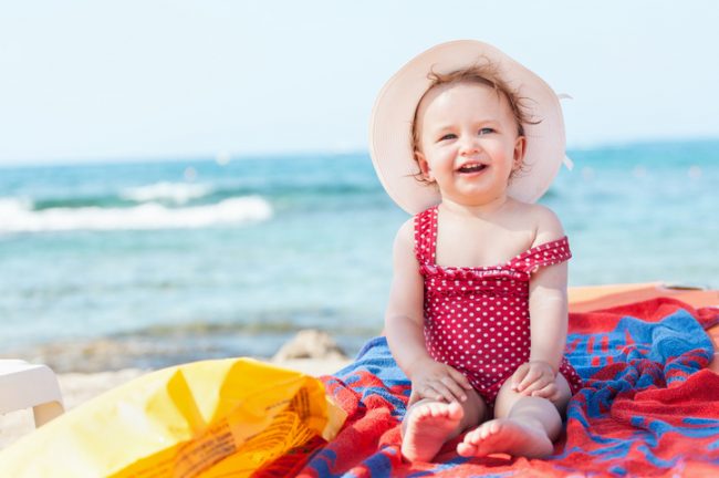 Baby on Beach in Red Swimsuit and Sunhat Protected by Natural Sunscreen | Vitacost.com/blog