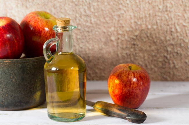 apple cider vinegar, apples and knife on table
