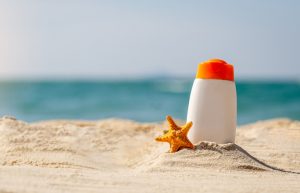 Small Starfish and Bottle of Coral Reef-Safe Sunscreen Pressed into Sand at Beach | Vitacost.com/blog