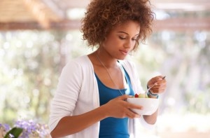 Woman Eating Fruit Salad Trying Remedies for Heartburn www.vitacost.com/blog