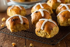 Hot cross buns on a wire rack on a wooden background