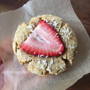 One coconut cookie with a strawberry slice on top on parchment paper