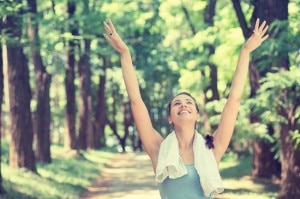 Woman exercising on wooded path with arms outstretched #exerciseandasthma | www.vitacost.com/blog