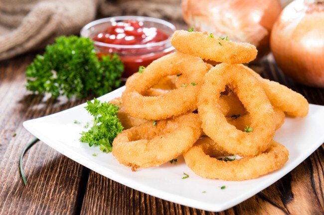 Pile of homemade, gluten-free onion rings on white plate #healthysnacks www.vitacost.com/blog