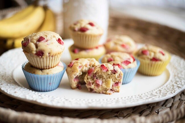 Healthy Strawberry-Banana Protein Muffins Strawberry muffins stacked on white plate with one cut open #healthy #recipe | www.vitacost.com/blog