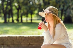 Woman in Hat Drinking Cranberry Juice for Bladder Health www.vitacost.com/blog