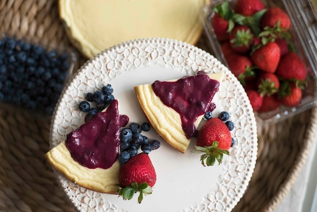 Coconut cheesecake with mixed berries & sauce on white cake stand #protein #recipe | www.vitacost.com/blog