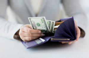 Woman Counting Money in Purple Wallet Saved by Healthy Living | Vitacost.com/blog
