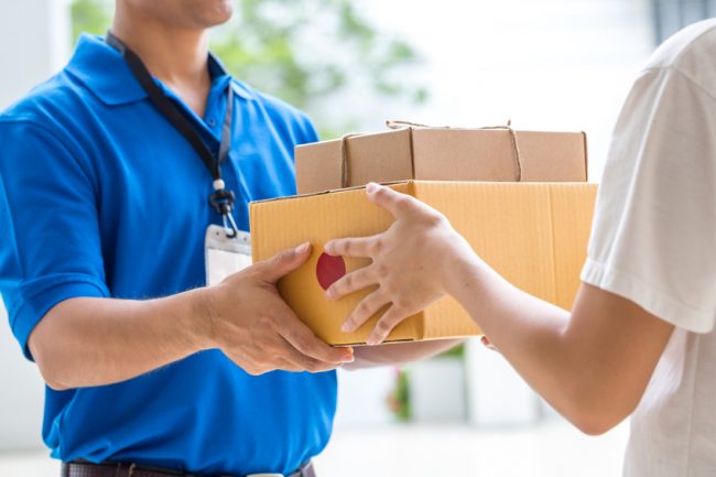 A female college student receiving a care package at her dorm from deliveryman | Vitacost.com/Blog