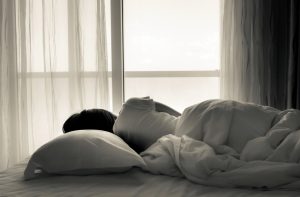 Woman Experiencing Melatonin Benefits Sleeping in Bed Beside Window | Vitacost,com/blog
