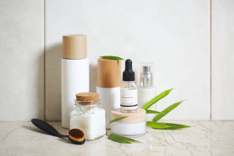 Natural Beauty Products with Greenery on Marble Surface to Represent Natural At-Home Facial Routine | Vitacost.com/blog