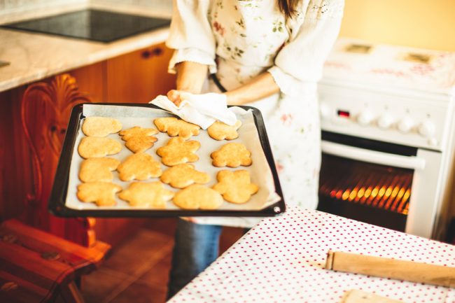 5 Best Gluten-Free Baking Tips Woman taking homemade gluten free cookies out of oven | Vitacost.com/Blog