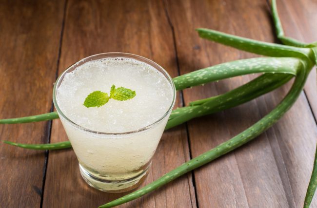 The Coolest New "Green" Drink: Benefits of Aloe Vera Juice Glass with Iced Aloe Drink and Aloe Leaves on Wooden Table | Vitacost.com/blog