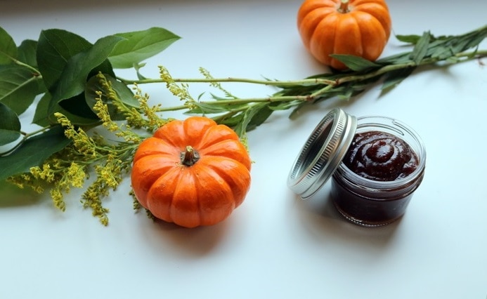 Homemade pumpkin spice sugar scrub in mason jar surrounded by fresh pumpkins | Vitacost.com/Blog