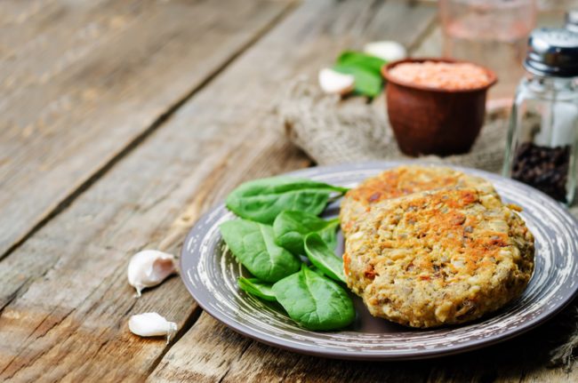 Oatmeal-Lentil Burgers Recipe  Vegan lentil-oat burger on plate with spinach | Vitacost.com/blog