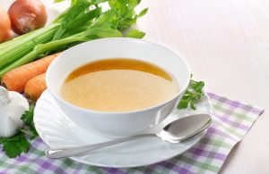 Bowl of Homemade Bone Broth on Checked Placement With Vegetables | Vitacost.com/blog