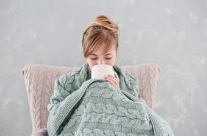 Woman Suffering From Cold Urticaria Bundled in Blanket Drinking Tea | Vitacost.com/blog