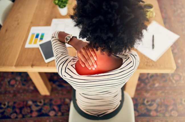 Woman at Desk Rubbing Neck as Part of Routine Health Self Assessment | Vitacost.com/blog