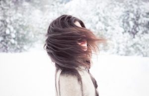 Woman with frizzy hair twirling in snow #frizzyhairtips | Vitacost.com/blog