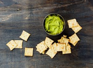 Homemade Crackers Spread out Around Avocado Dip on Wood | Vitacost.com/blog