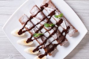 3 Cassava Flour Crepes on a White Plate with Chocolate Drizzle & Banana Coins #recipe | Vitacost.com/blog