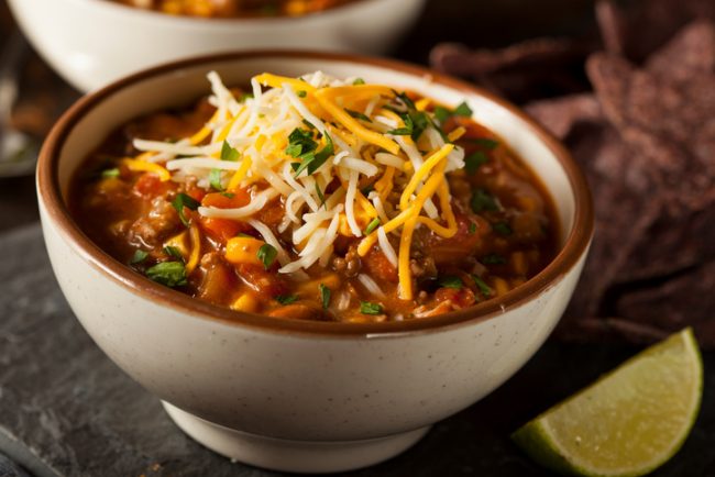 Easy Chicken Tortilla & Black Bean Soup  Chicken & black bean soup in white bowl with cheese and lime wedge