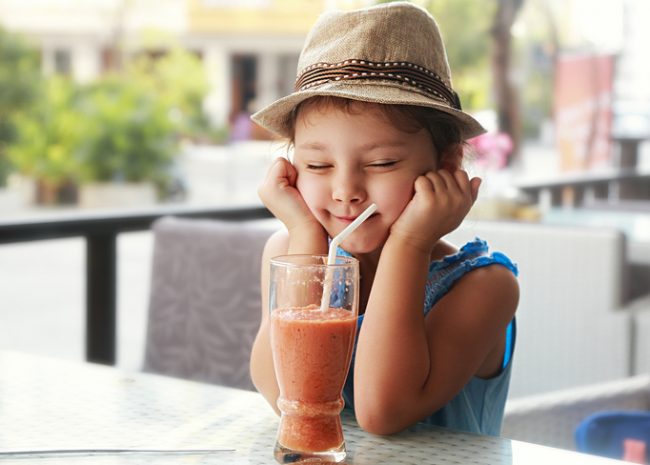 Fiber for Kids: Best Foods to Make Sure They're Getting Enough Child in Hat at a Cafe Table Sipping a High Fiber Snack Smoothie | Vitacost.com/blog