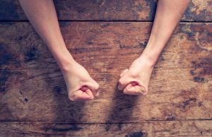 Woman in Need of Anger Management Tips With Fists Clenched on Wooden Table | Vitacost.com/blog