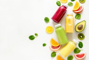 Example of Detox Kit Containing Vibrant-Colored Juices, Fruit Slices and Green Leaves on White Surface | Vitacost.com/blog