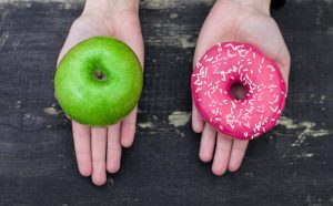 Holding Apple and Donut in Hands Trying to Make Top Nutrition Choice | Vitacost.com/blog