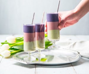 Woman Picks One of Three Tri-Colored Fruit Smoothie Glasses from Silver Tray | Vitacost.com/blog