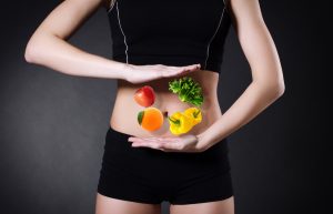 Woman Demonstrating Digestive Enzymes Benefits With Hands Over Fruit on Belly | Vitacost.com/blog