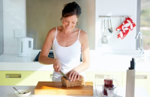 Smiling Woman Cutting Loaf of Bread as Part of a Healthy Diet to Fight Depression | Vitacost.com/blog
