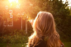 Blonde Woman Outside Blows Bubbles, Thinking About Keratin or Biotin for Hair Benefits | Vitacost.com/blog