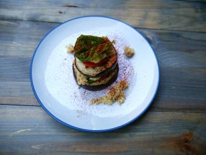 Eggplant Slices Stacked with Parmesan, Tomatoes & Basil on White Plate, Wood Table #recipe | Vitacost.com/blog