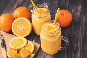 Citrus Fruit Smoothie in Glass Jars with Fresh Orange Slices on Wood Background | Vitacost.com/blog