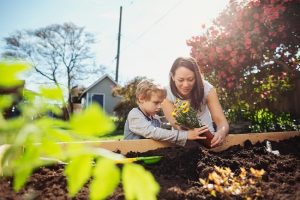 Woman Plants Flowers with Son, Showing How to Help the Environment with Plant-Based Diet | Vitacost.com/blog