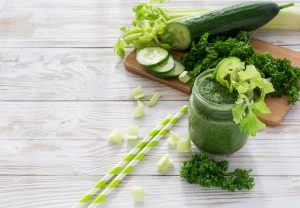Green Spirulina Smoothie on White-Washed Wood with Straws & Cut Vegetables #recipe | Vitacost.com/blog