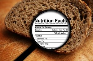 Magnifying Glass Over Bread Slice Highlighting Deceptive Food Label | Vitacost.com/blog