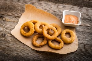 Onion Rings on Parchment Paper with Sauce on Wood | Vitacost.com/blog