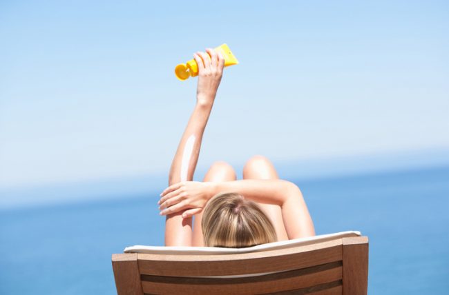 Woman at Beach Applying Sunscreen to Follow Summer Skin Care Tips | Vitacost.com/blog
