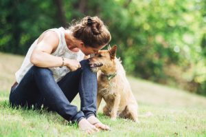 Woman Following Summer Safety Tips for Pets Petting Dog in Grassy Field | Vitacost.com/blog