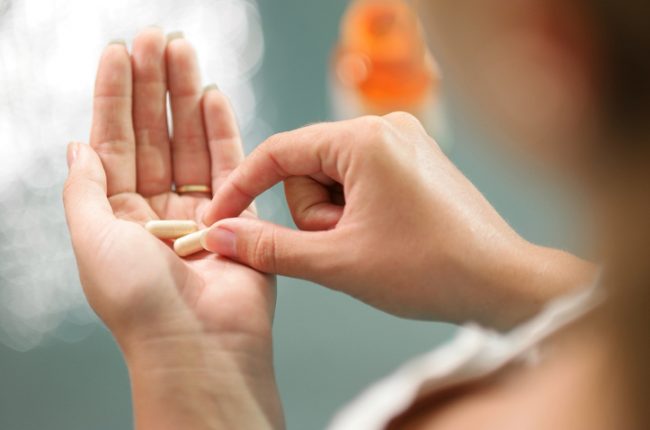 Post-Menopausal Woman Holding Essential Vitamins for Women in Palm of Hand | Vitacost.com/blog