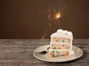 Slice of Gluten-Free Rainbow Confetti Cake with Lit Sparkler on Plate | Vitacost.com/blog