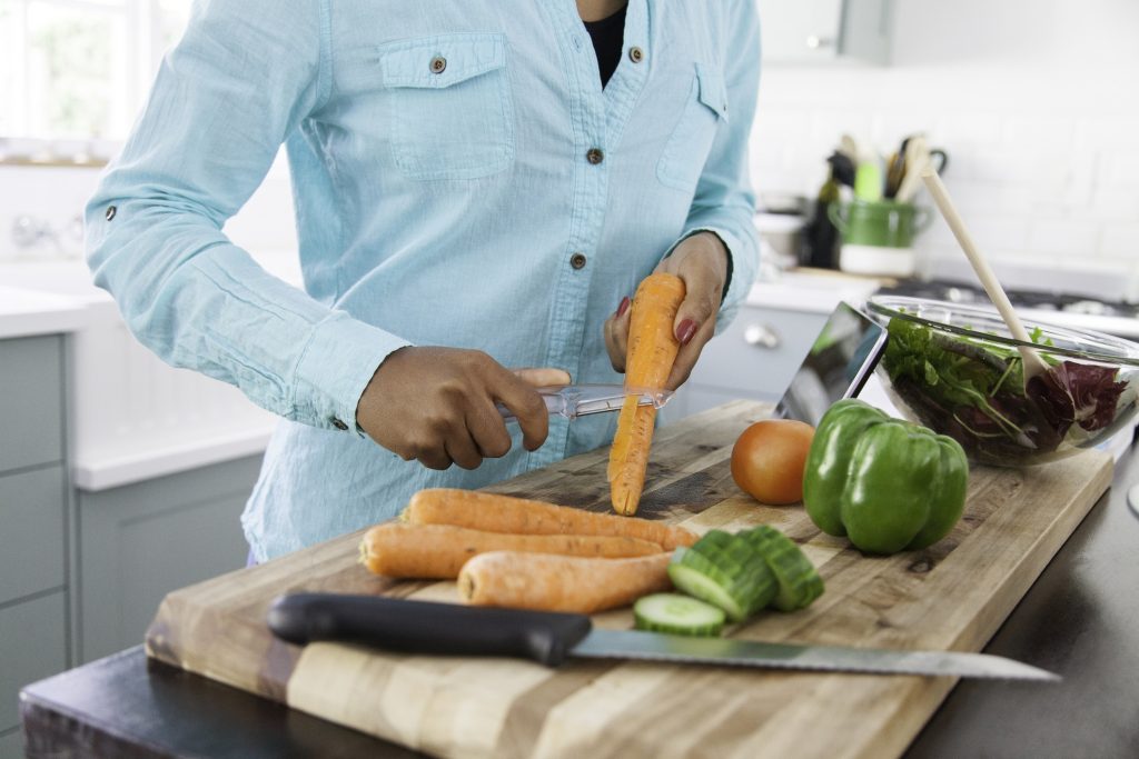 Woman in Kitchen Prepares Weight-Loss Meal Plan by Cutting Carrots for Salad | Vitacost.com/blog