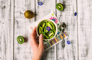 Bowl of Sliced Kiwi Fruit on White Wooden Table as Example of Cooling Foods to Reduce Body Heat | Vitacost.com/blog