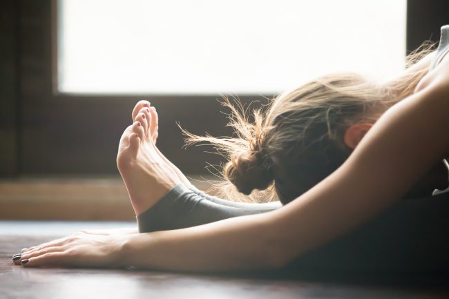 Woman Practicing Yoga in Forward Folded Bend to Relieve Anxiety | Vitacost.com/Blog