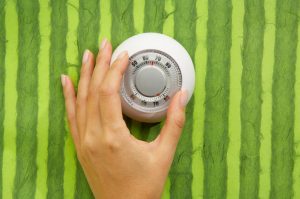 Hand Turning Up Temperature on Thermostat to Save Energy for Summer | Vitacost.com/blog