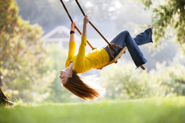 Woman Celebrating Healthy Aging Swinging Playfully in Backyard | Vitacost.com