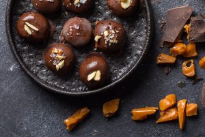 Several Chocolate Protein Balls with Salt & Almonds on Black Plate with Caramel Pieces | Vitacost.com/blog